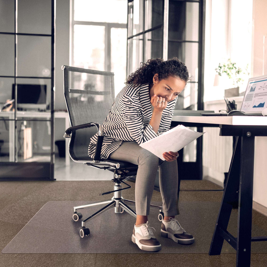 This picture is showing a lady useing the pvc protective desk chair  mat while using her computer and focusing on her work.