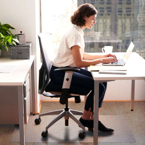 Picture showing a wowman using her desk  with the protective floor mat for her office desk chair.