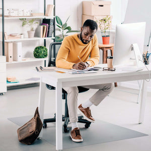 Picture showing the man using  his home office desk chair with the protective floor mat for hard floor.