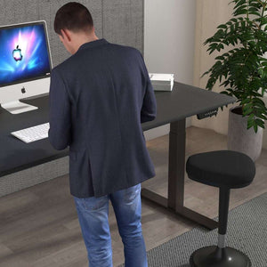 Picture showing a man using the air height adjustable desk in black in his home office.