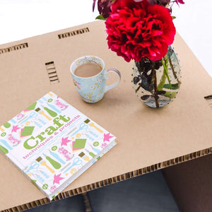 Showing you the eco desk with flower vase and a cup of tea and being used for art work .